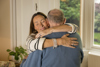 Image of a carent hugging her older father, in the midst of caring for him, her elderly parent