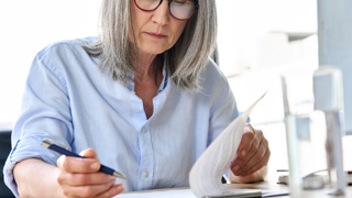 Woman in her 60s signing documents. These represent legal proceedings your elderly parent will encounter.