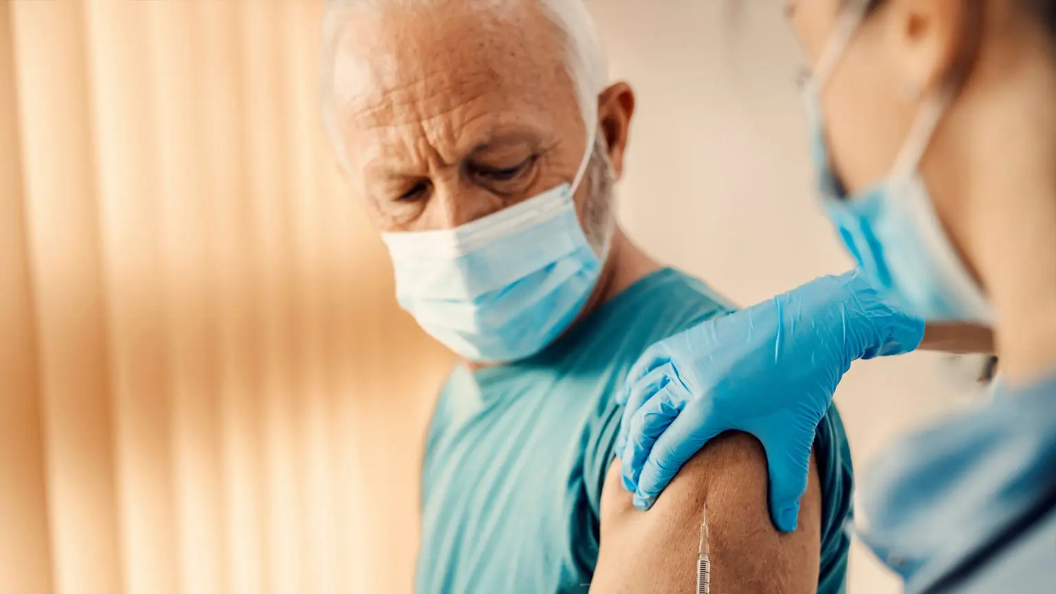 Older man receiving shingles vaccine from a healthcare worker — shingles vaccination may help reduce dementia risk