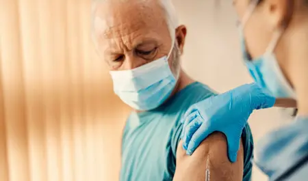 Older man receiving shingles vaccine from a healthcare worker — shingles vaccination may help reduce dementia risk