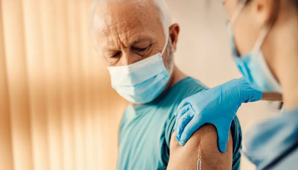 Older man receiving shingles vaccine from a healthcare worker — shingles vaccination may help reduce dementia risk