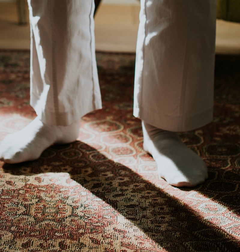 Older adult wearing socks while using a walking stick – sock aids help elderly parents with limited flexibility or balance to put on socks independently without bending or straining.