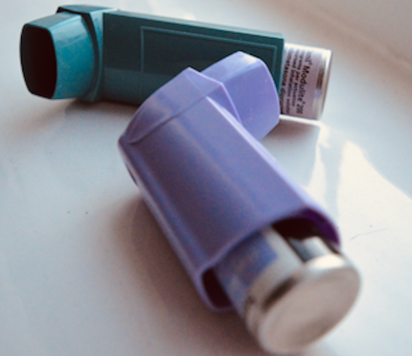 Two inhalers on a surface - one is blue, the other purple
