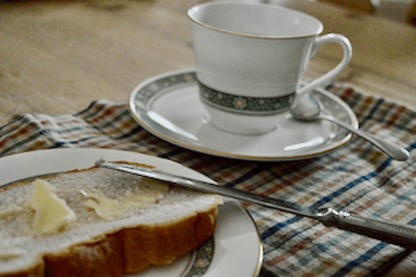 Butter and bread with a tea cup and saucer nearby