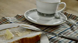 Butter and bread with a tea cup and saucer nearby