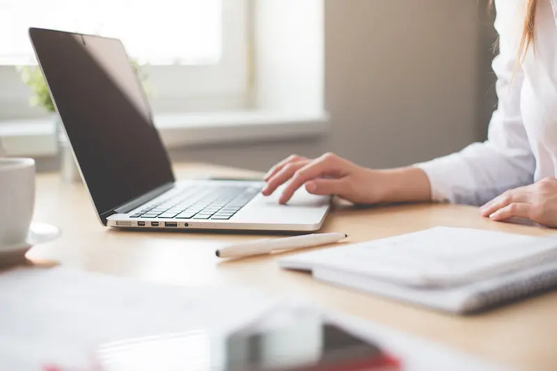 Woman sitting at a laptop with items strewn across the desk