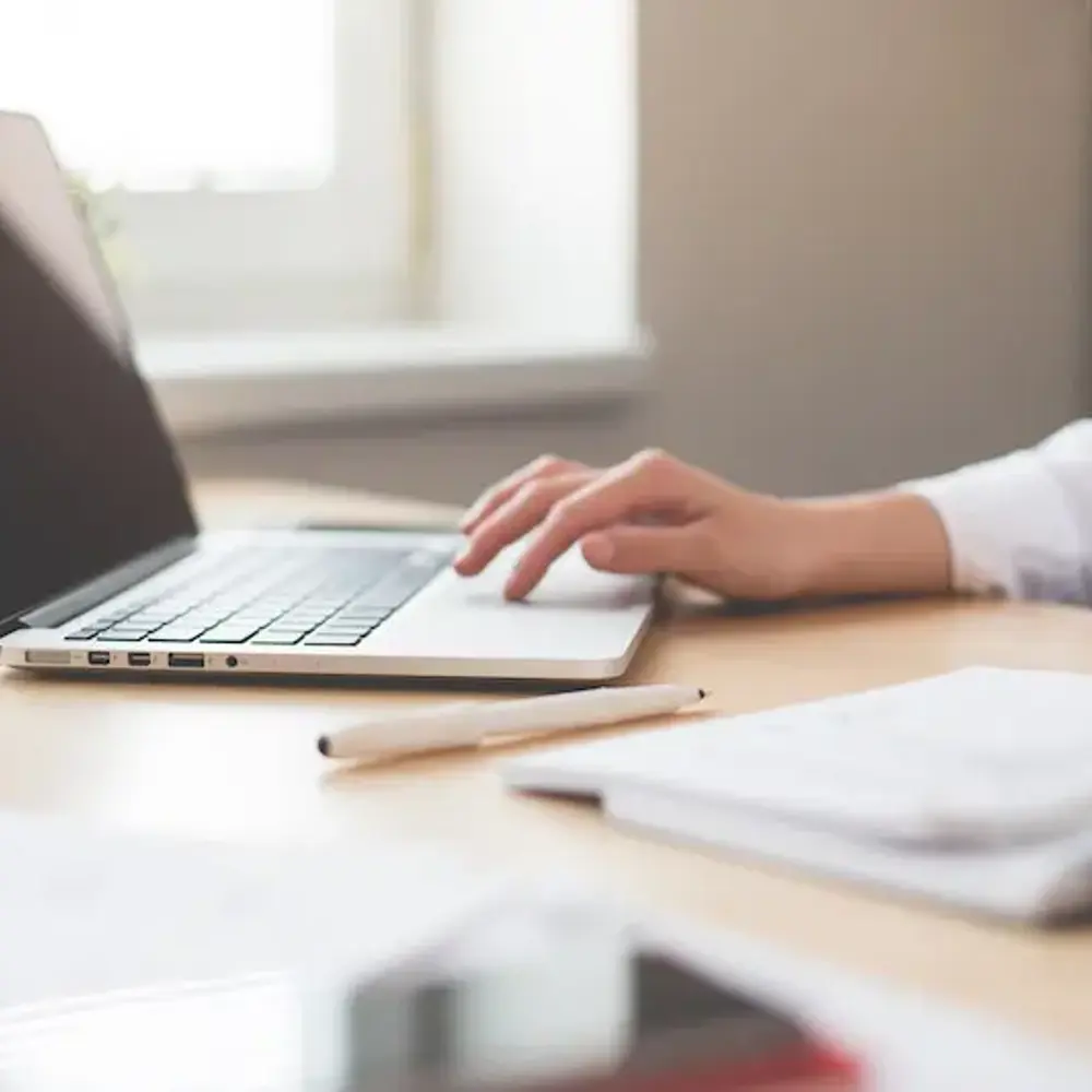 Woman sitting at a laptop with items strewn across the desk