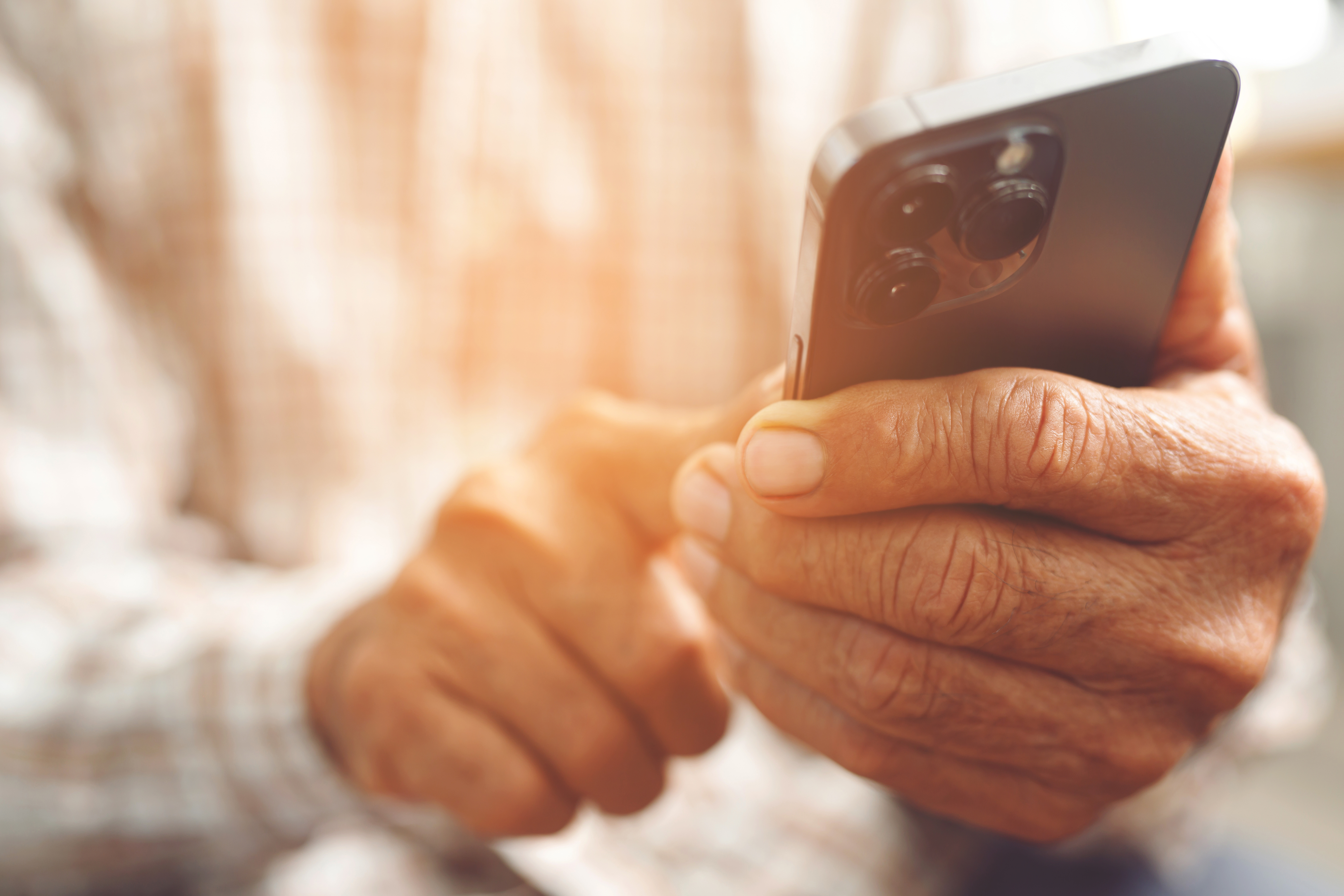 Close-up of an older adult using a modern smartphone –  choose easy-to-use mobile or landline phones for elderly parents needing clear displays and simple features.