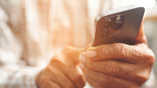 Close-up of an older adult using a modern smartphone –  choose easy-to-use mobile or landline phones for elderly parents needing clear displays and simple features.