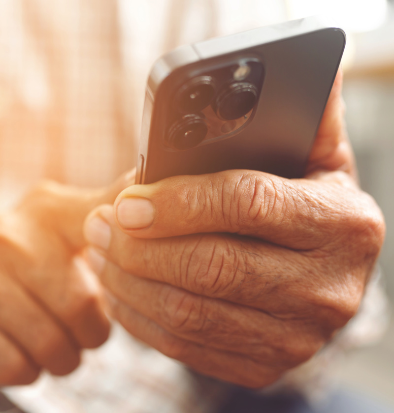 Close-up of an older adult using a modern smartphone –  choose easy-to-use mobile or landline phones for elderly parents needing clear displays and simple features.