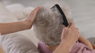 Carer gently combing an older adult’s hair – waterless hair products are a convenient option for elderly parents who have limited mobility or find regular hair washing difficult.