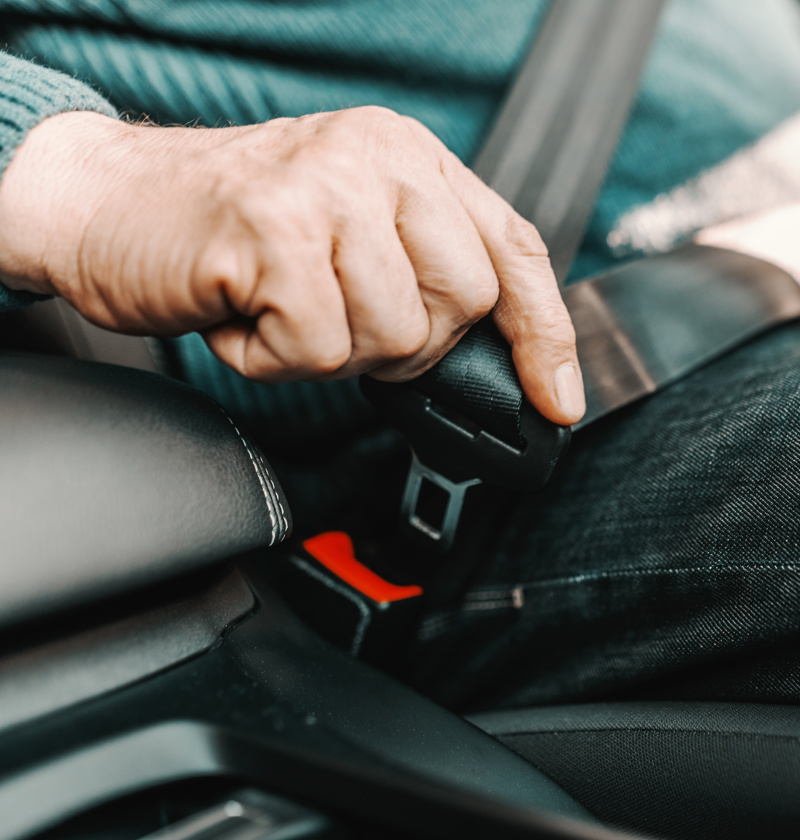 Older adult fastening a car seat belt – seat belt assists help elderly parents with limited reach or grip strength buckle up more easily and safely when getting into a vehicle.