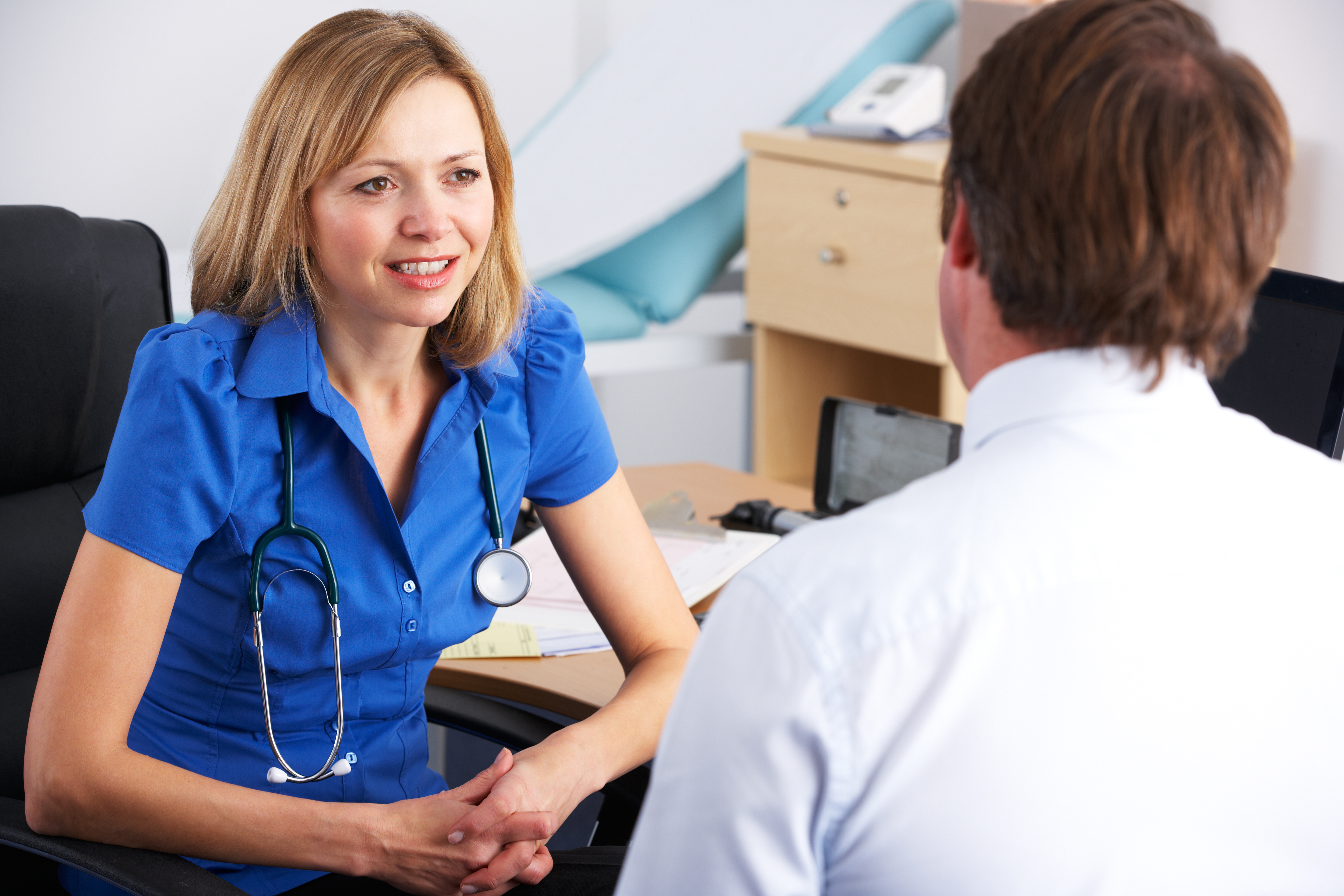 Consulting a GP About Elderly Parent’s Health – A female doctor in a blue uniform listens attentively to a patient. A reminder of the importance of regular check-ups and seeking professional medical advice for elderly loved ones.