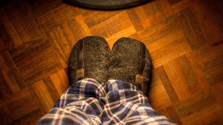 Close-up of an older adult wearing warm, cushioned slippers indoors – comfortable slippers help elderly parents stay steady on their feet while keeping warm, especially on hard flooring.