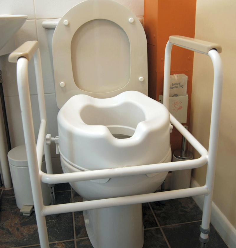 Toilet fitted with a raised seat and support frame – toilet seat risers help elderly parents with limited mobility sit and stand more easily, reducing strain and supporting safer bathroom use.