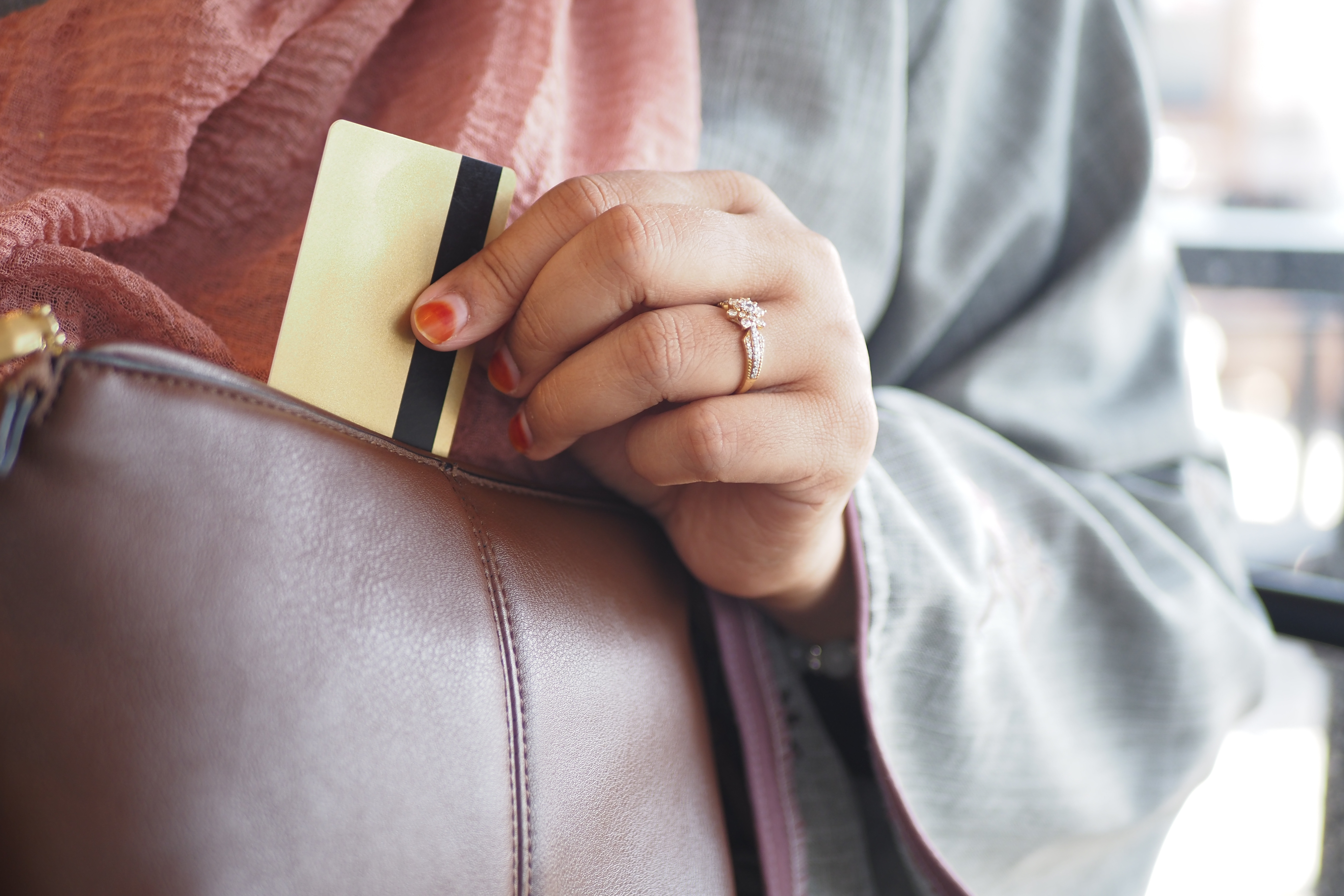 Paying for Care: Budgeting for Elderly Support – A close-up of a woman retrieving a credit card from her handbag, representing financial decisions, care home payments, and budgeting for elderly relatives.