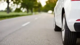 A road with a white car driving down it