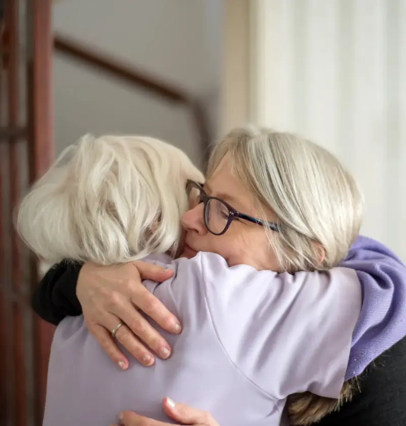 A middle aged woman hugging her elderly parent