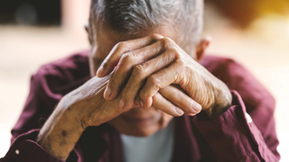 An elderly man with his head in his hands. Represents feelings of loneliness or depression, both of which an elderly parent could be.