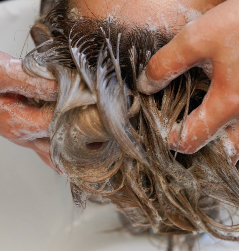 Carer washing an older adult’s hair over a basin – hair washing trays make it easier to wash hair for elderly parents with limited mobility, reducing the need to bend or move to a shower.