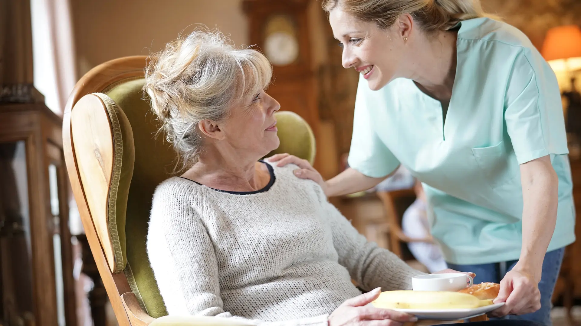 Elderly parent in a care home being given food by a residential carer