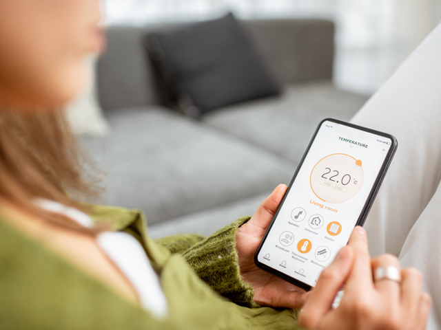 Someone reading their thermostat on their phone. Smart heating system. Representing heating, energy awareness, bills and PSR entitlement for your elderly parent.