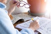 Older adult holding reading glasses while completing a puzzle in a dementia activity book – these books support memory, focus, and enjoyment for elderly parents living with cognitive decline.