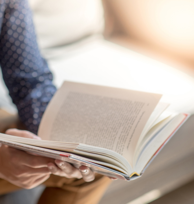 Person reading a book to learn more about caring for an elderly parent