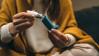 woman sitting down and looking at an inhaler