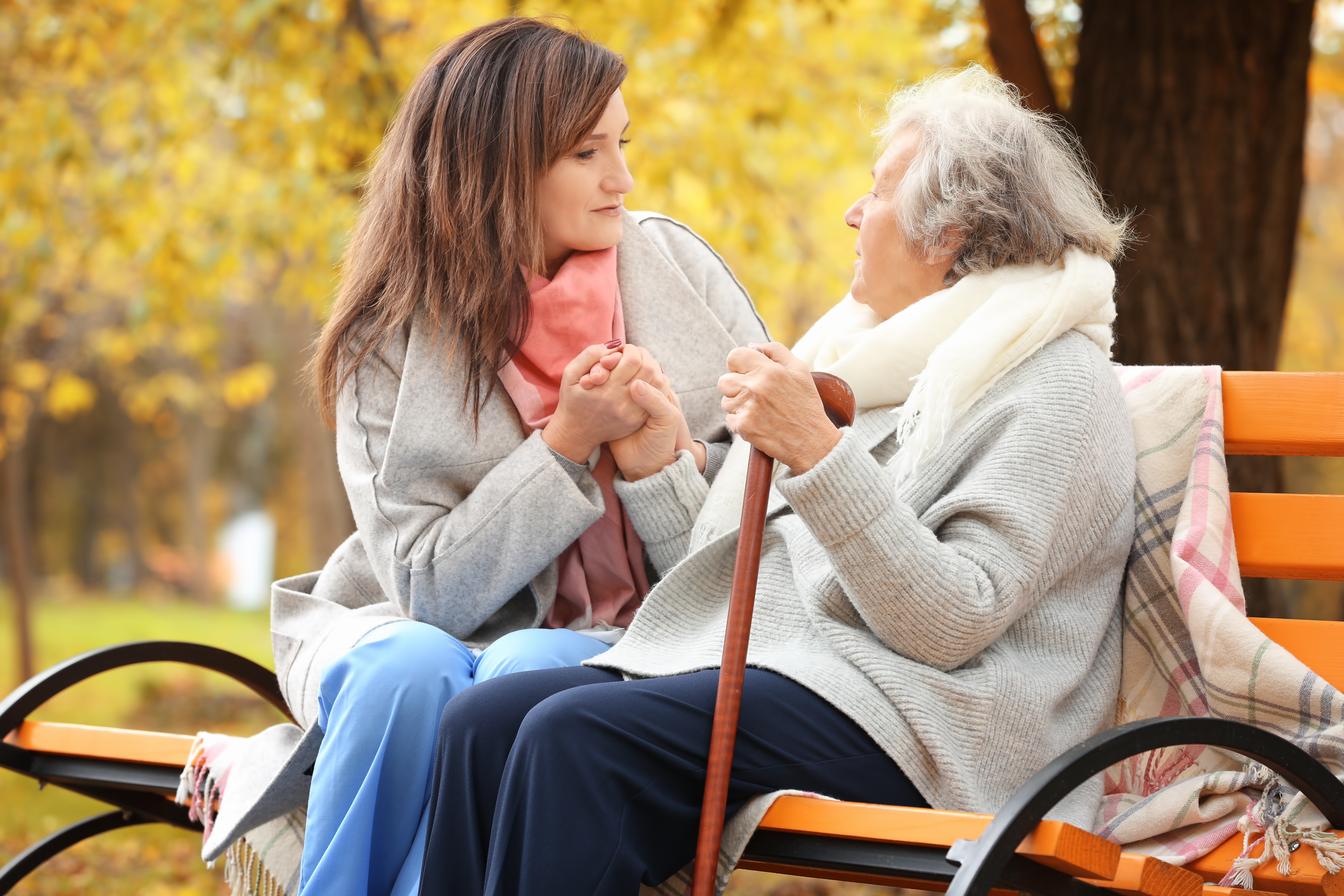 Carent and their elderly parent sitting on a bench