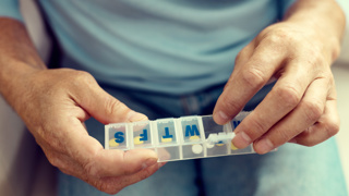 Weekly pill dispenser for elderly parents – older adult using a daily pill organiser with labelled compartments to manage medication safely and independently at home.